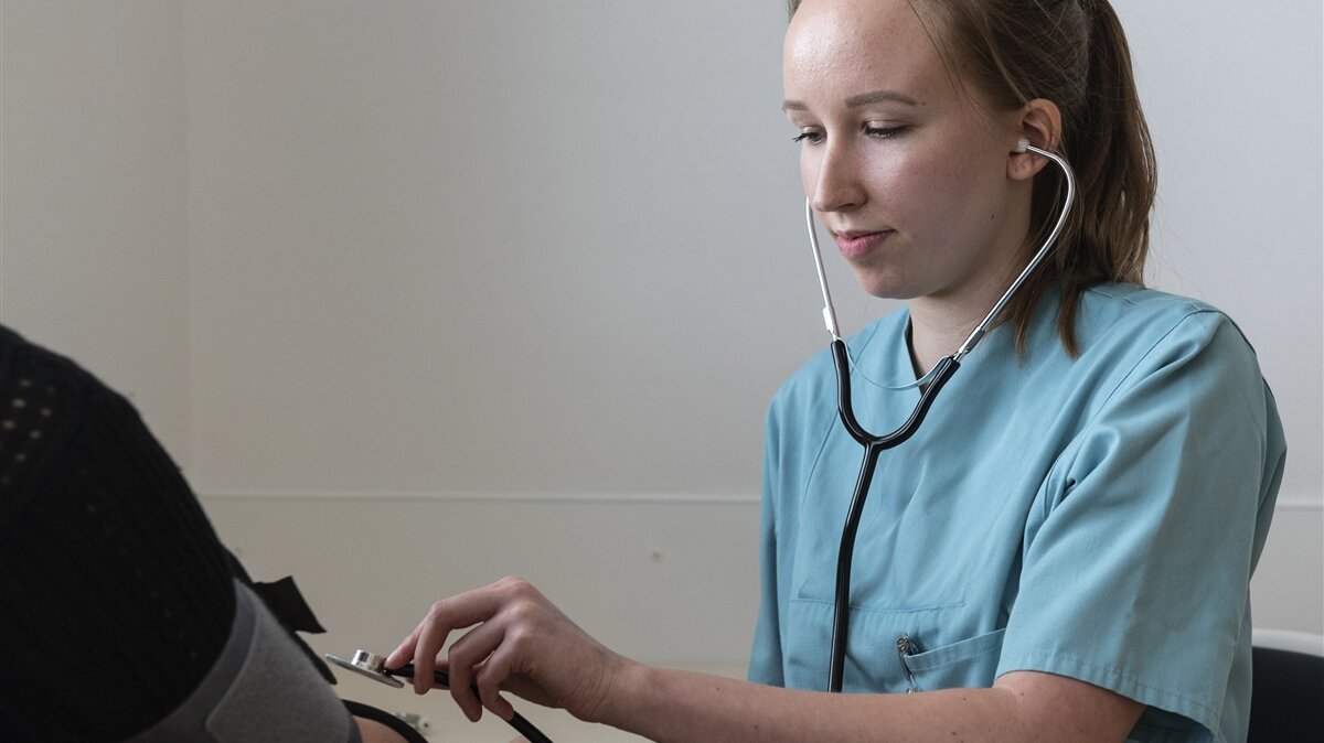 Lena misst den Blutdruck einer Patientin.