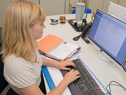 Eine junge Frau arbeitet an einem Laptop.