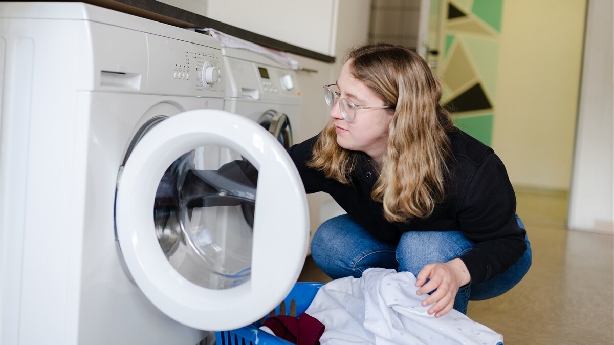 Leonie-Marie räumt Wäsche aus einer Waschmaschine. 