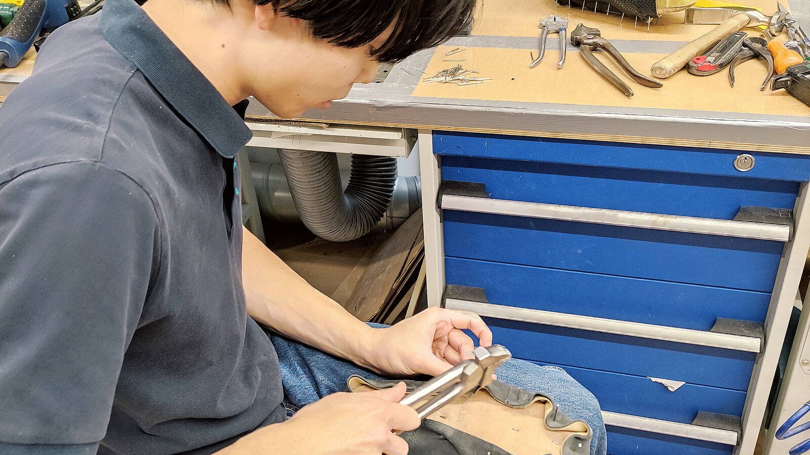 Tsuyoshi arbeitet miteiner Zange das Leder des Schuhs.