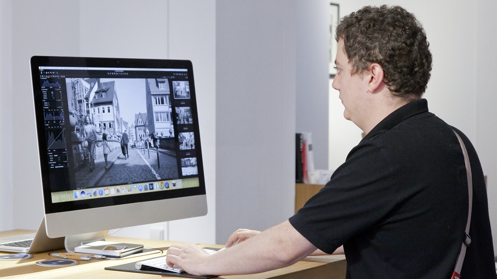 John bearbeitet Kundenbilder am Mac, stellt Sättigungen, Schärfen und Kontraste ein, bevor diese entwickelt/gedruckt werden.