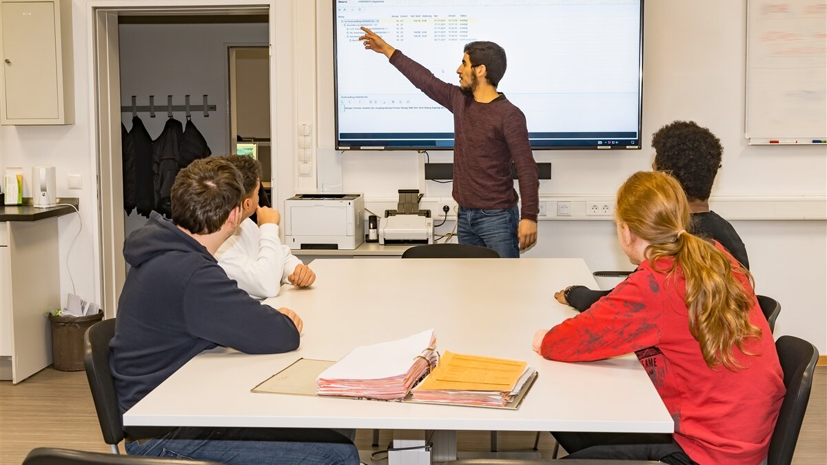 Ein Mathematisch-technischer Assistent hält eine Schulung für seine Kolleginnen und Kollegen. 