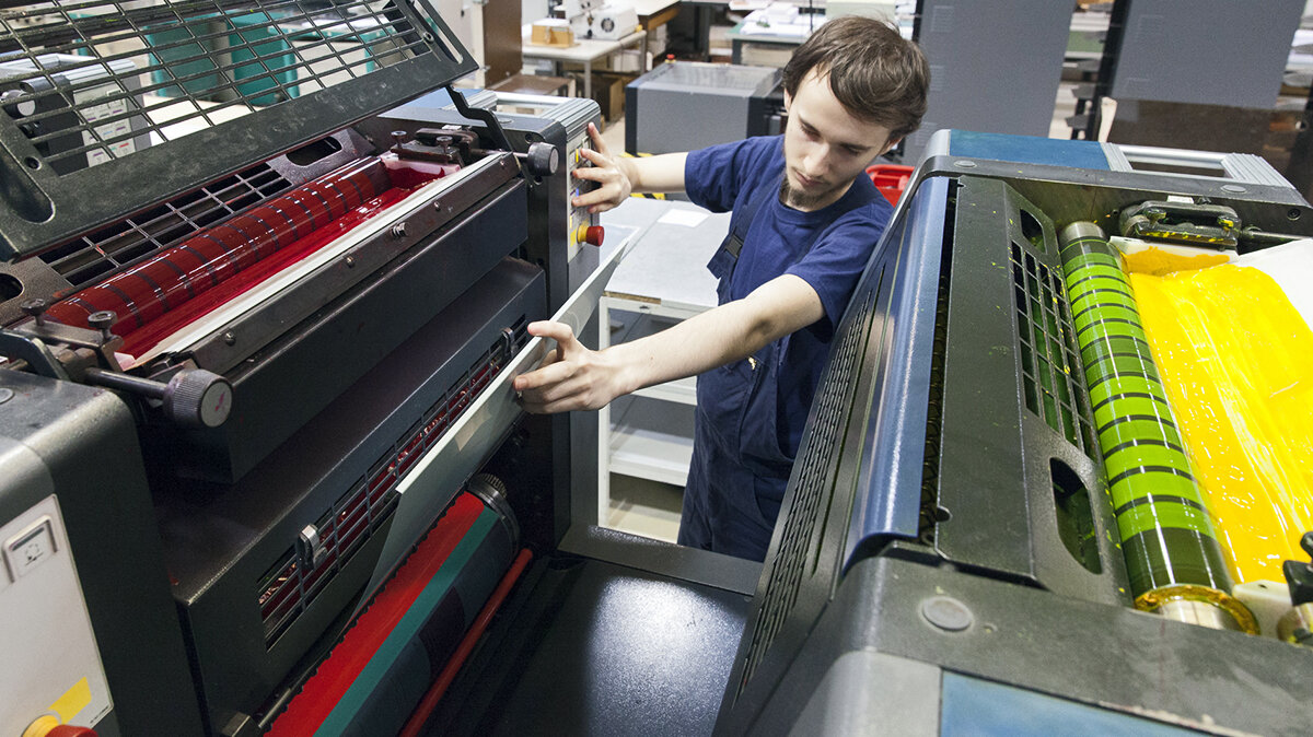 Ein junger Mann überprüft eine Mediendruckmaschine
