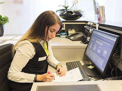 Eine junge Frau arbeitet mit einem Programm am Computer.