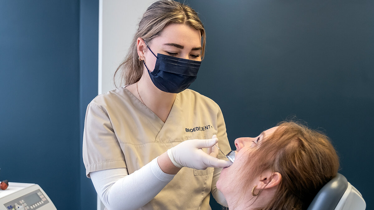 Karolin trägt Schutzausrüstung und macht einen Gebissabdruck bei einer Patientin.