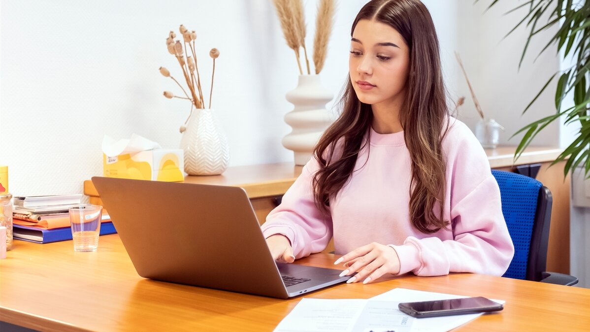 Eine junge Frau arbeitet am Laptop.