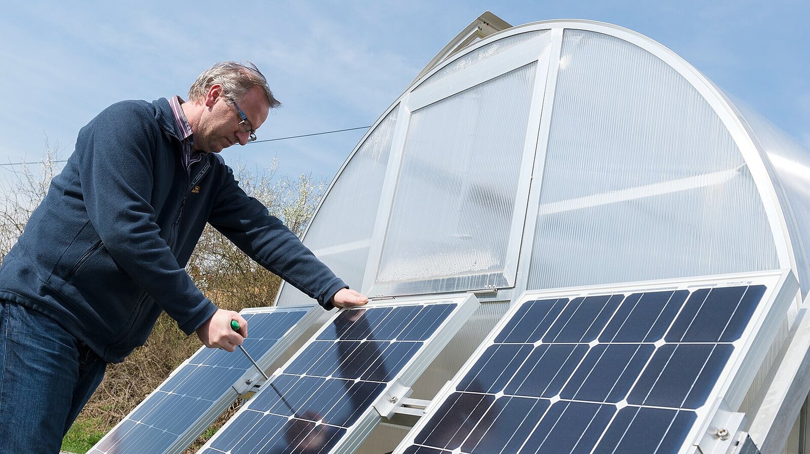 Ein Mann montiert eine Demonstrationsanlage für Photovoltaik.