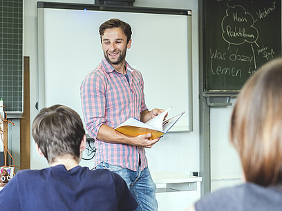 Ein Lehrer steht vor einer Tafel und unterrichtet seine Klasse.