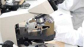 Ein Laborant untersucht Proben mit einem Mikroskop.