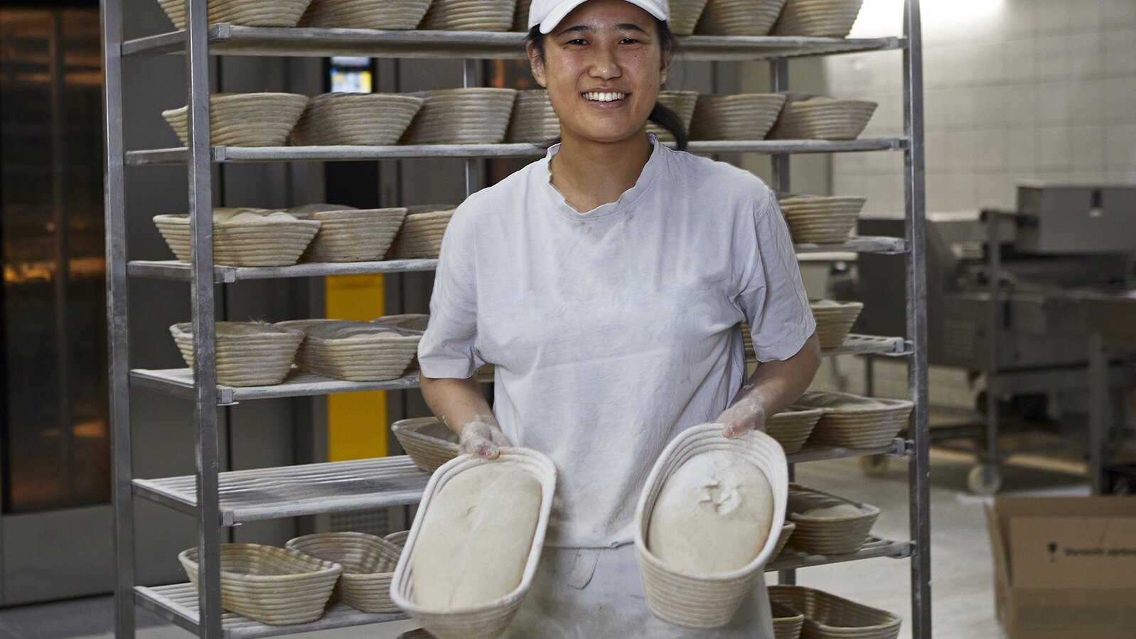 Porträt von Nanase mit ungebackenen Brotlaiben, die in Formen sind.