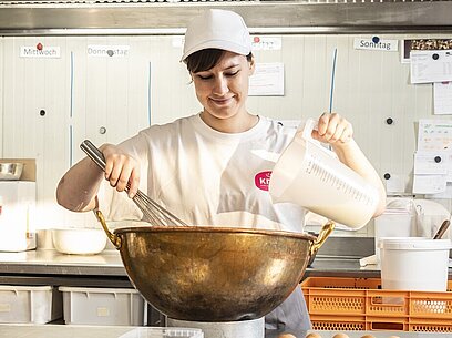 Eine junge Frau verrührt Zutaten in einer großen Backschüssel