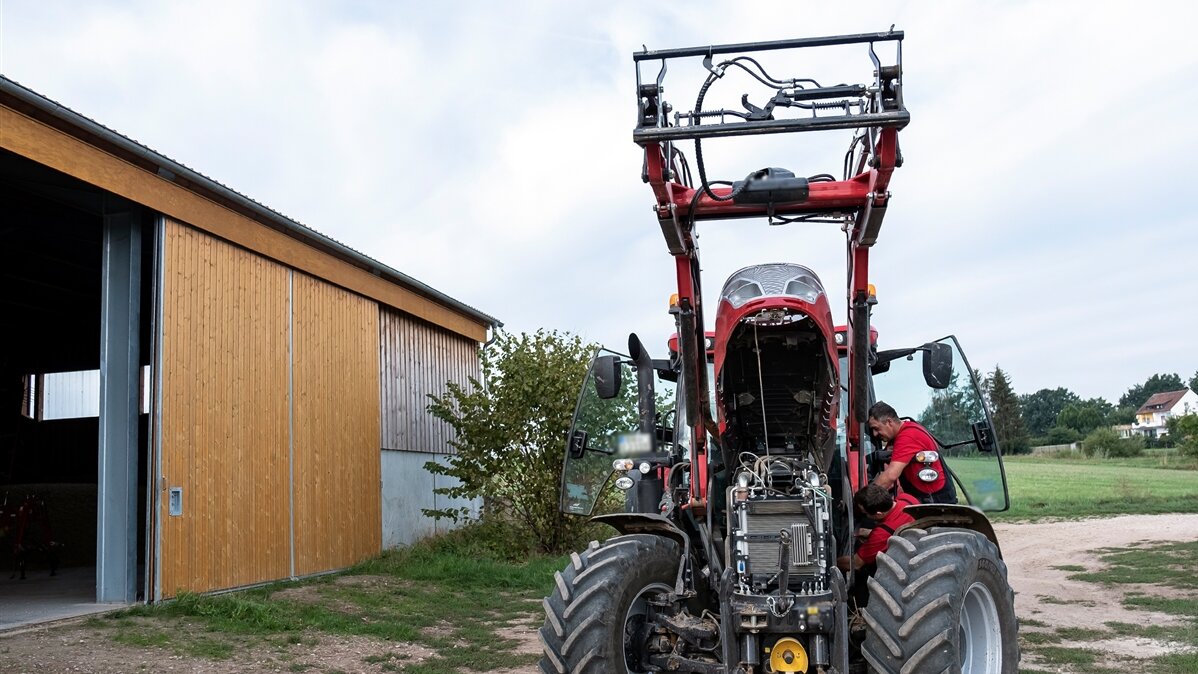 Ein Traktor steht vor einem Stall.