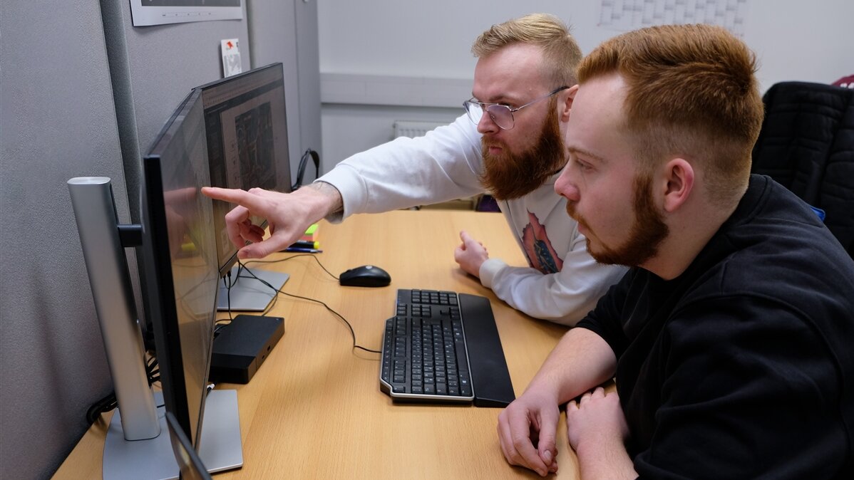 Simon und ein Kollege besprechen einen Schadenfall am Computer.