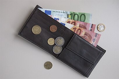 Aufnahme eines Geldbeutels mit Scheinen und Münzen von oben