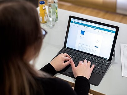 Eine Jugendliche schreibt am Laptop.