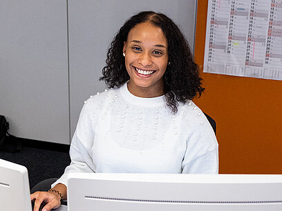 Eine junge Frau arbeitet an einem Computer mit zwei Bildschirmen.