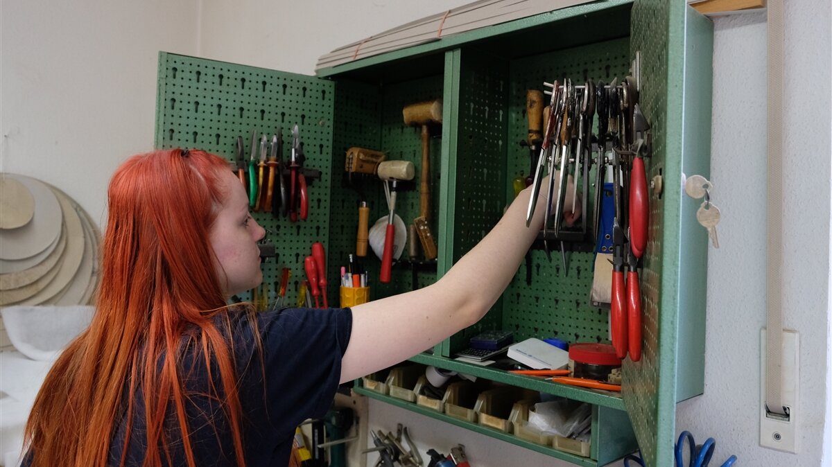 Corvina räumt die benutzten Werkzeuge zurück in den Schrank.