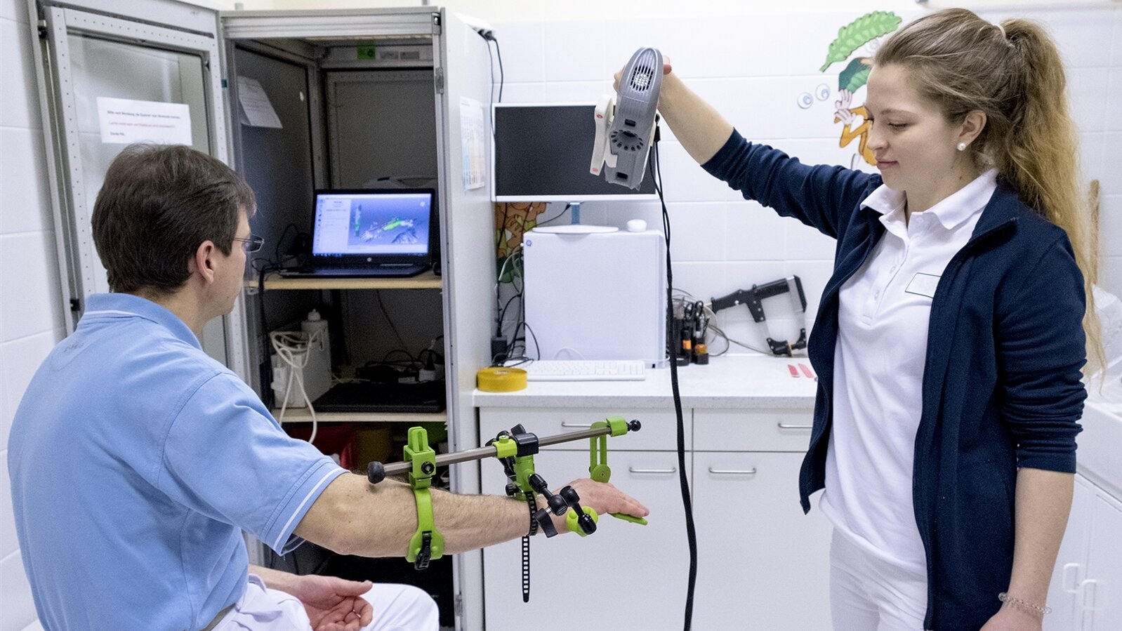 Eine Orthopädietechnik-Mechanikerin scannt einen Kunden für eine Handorthese.