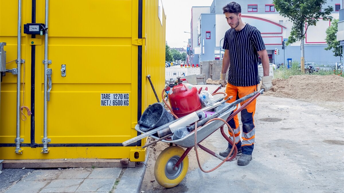 Jaafar räumt das Werkzeug in einen Baucontainer.