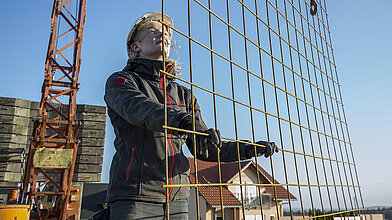 Eine junge Frau stellt auf einem Dach ein Gitternetz auf. 