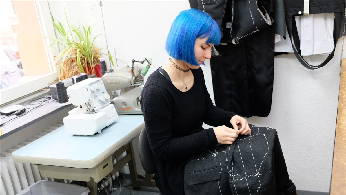 Eine Modedesignerin prüft ein Kleidungsstück.