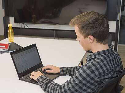 Ein junger Mann arbeitet am Laptop.
