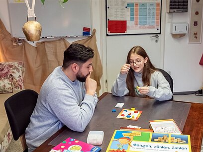 Eine junge Frau spielt mit zwei älteren Menschen ein Brettspiel.