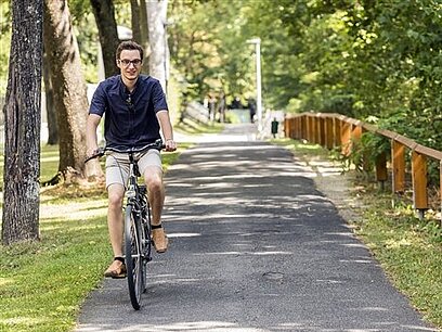 Ein junger Mann fährt auf einem Weg Fahrrad.