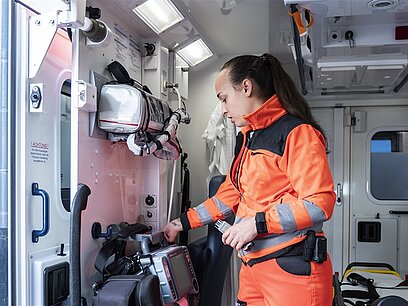 Eine junge Frau in Uniform überprüft eine Maschine in einem Krankenwagen.