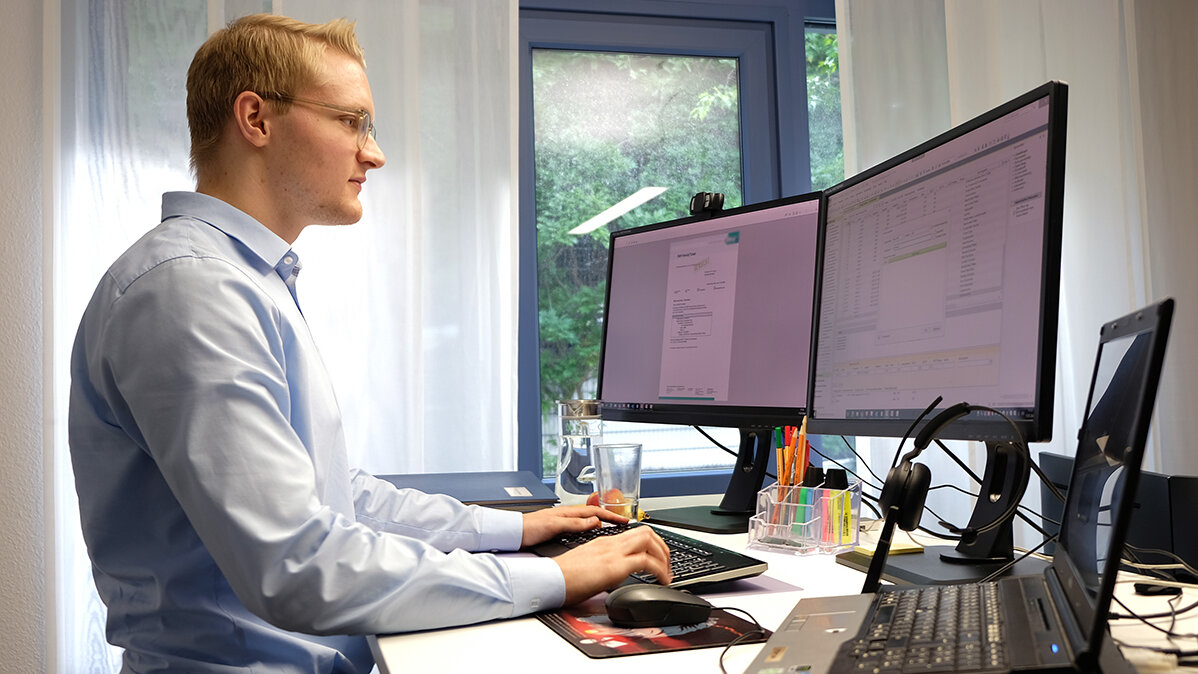 Jonas steht vor dem Computer und gibt Daten in ein Programm ein.