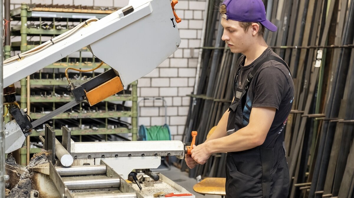 Luca spannt das Rundmaterial aus Aluminium in die Bandsäge ein.