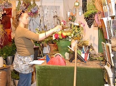 Eine junge Frau bindet Blumen.