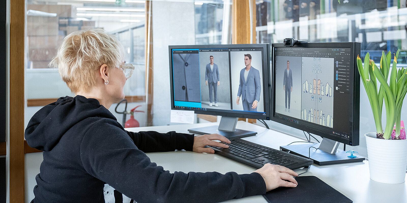 Eine junge Frau designt Kleidung an einem Computer.