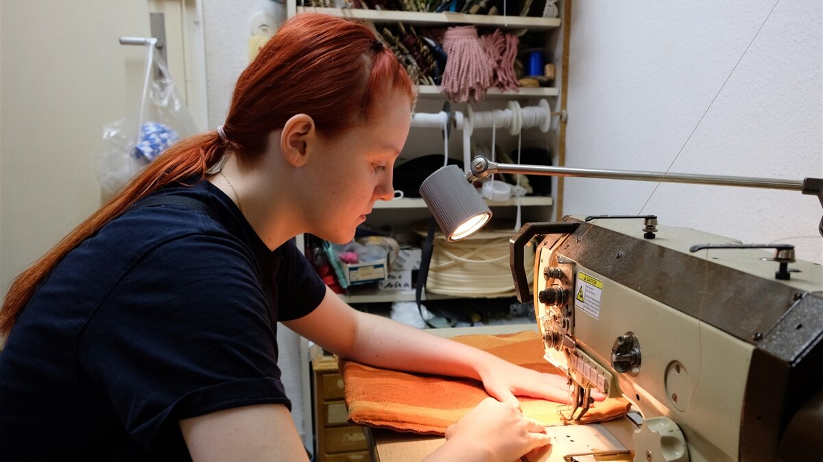 Eine junge Frau arbeitet an einer Nähmaschine.
