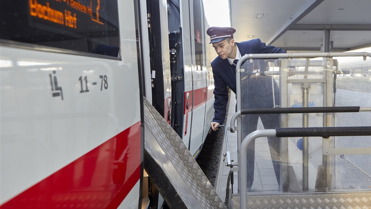 Ein junger Mann fährt eine Rollstuhlrampe an die Tür eines Zuges.