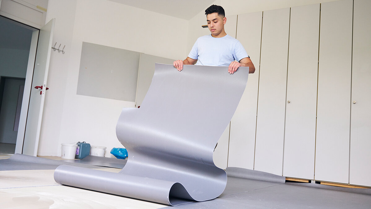 Ein junger Mann legt PVC-Boden aus.