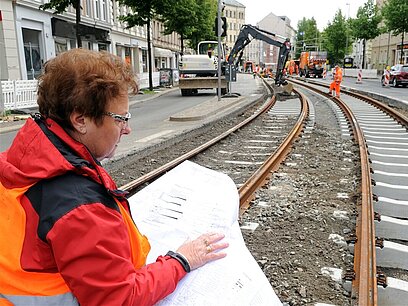 Eine Frau bereitet mit Hilfe von Plänen die Gleisbauarbeiten vor.