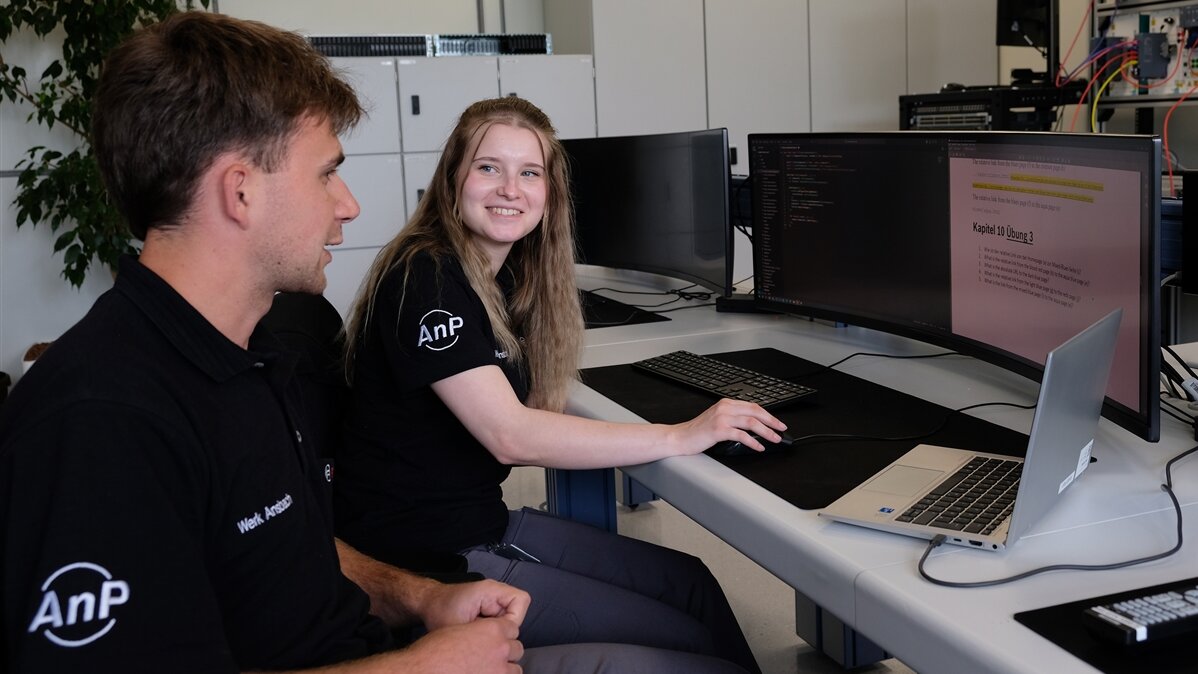 Ayliah und ihr Kollege arbeiten gemeinsam am Computer.
