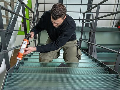 Ein junger Mann führt Feinarbeiten an einer Treppe mit Glasstufen aus.