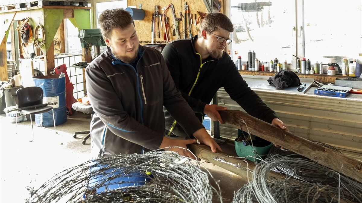 Jonathan und ein Kollege beladen den Transporter mit Drahtrollen und Holzpfählen.
