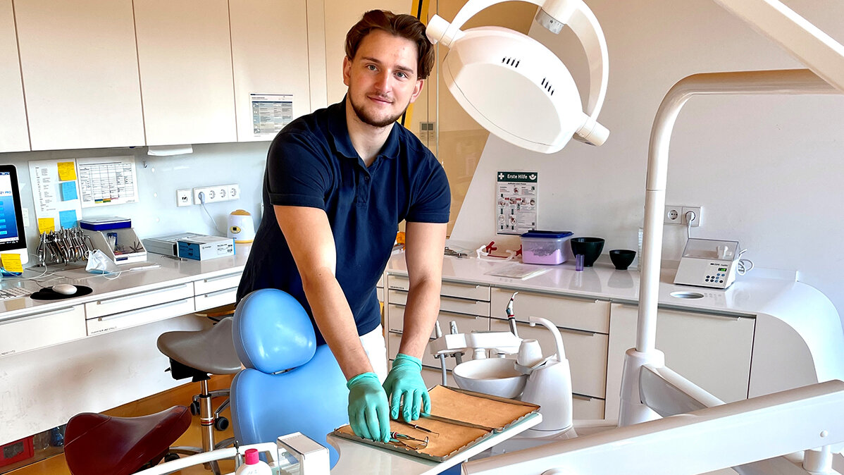 Dino trägt Schutzhandschuhe und bereitet im Behandlungszimmer der Zahnarztpraxis Instrumente vor.