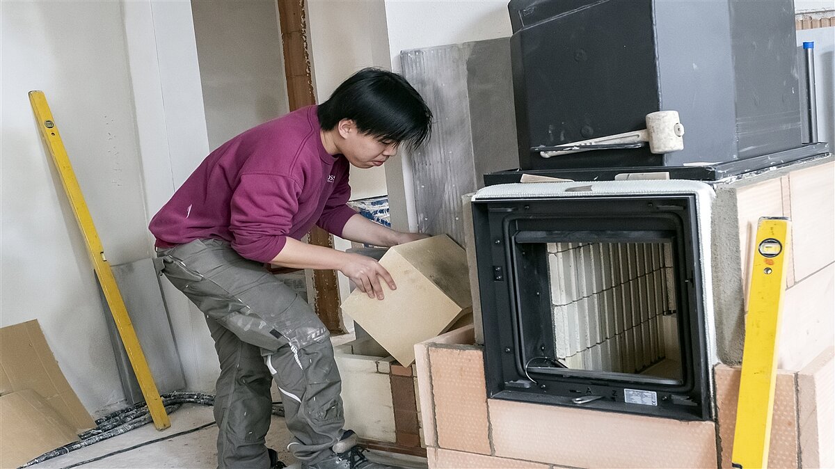 Hao mauert auf der Baustelle die Rauchgaszüge eines Grundofens.
