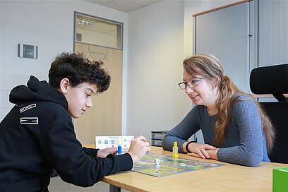 Eine Junge Frau spielt mit einem Jungen ein Brettspiel.