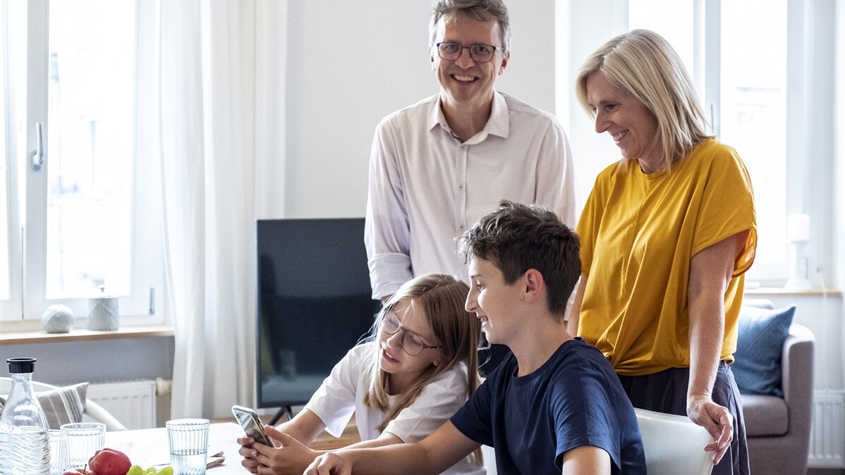 Eine Familie sieht sich etwas auf einem Smartphone an.