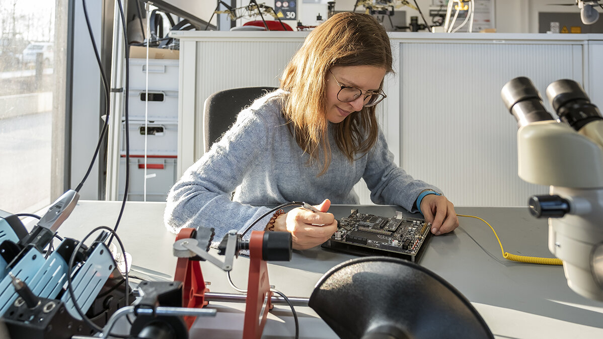 Eine Ingenieurin untersucht eine elektronische Leiterplatte.