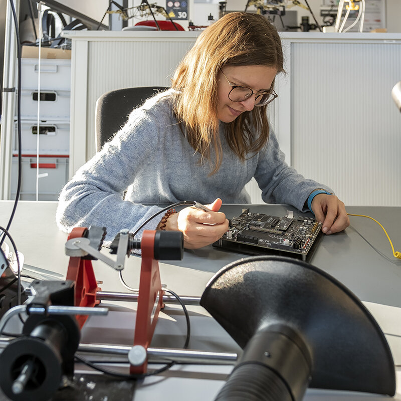 Eine Ingenieurin untersucht eine elektronische Leiterplatte.