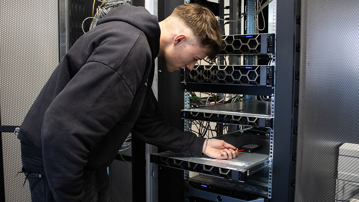Paul löst die Schrauben einer Festplatte, um sie aus dem Serverschrank auszubauen.