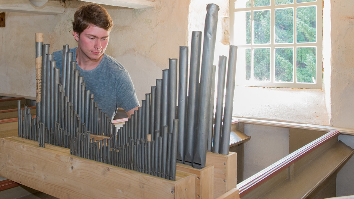 Johannes arbeitet an Holzrastern mit Orgelpfeifen.