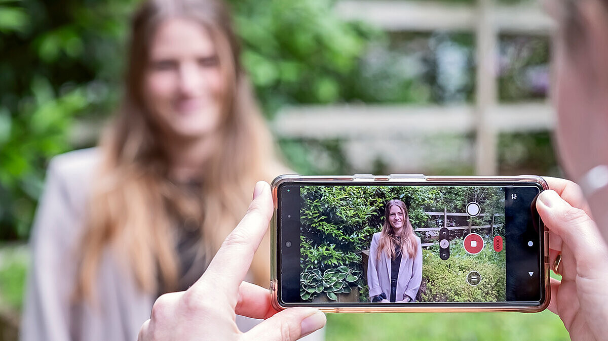 Eine Person filmt eine andere Person mit einem Smartphone.