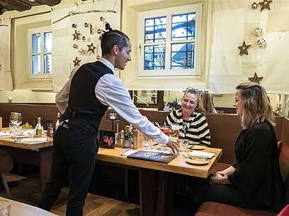 Ein junger Mann bedient zwei junge Frauen im Restaurant.